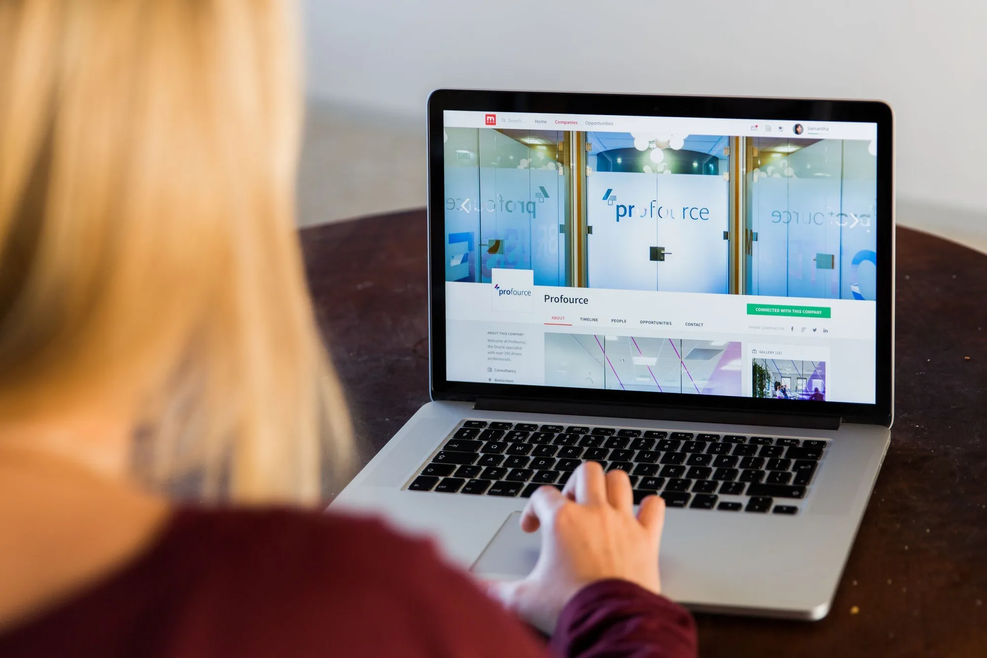 A woman viewing a company profile on a laptop screen.